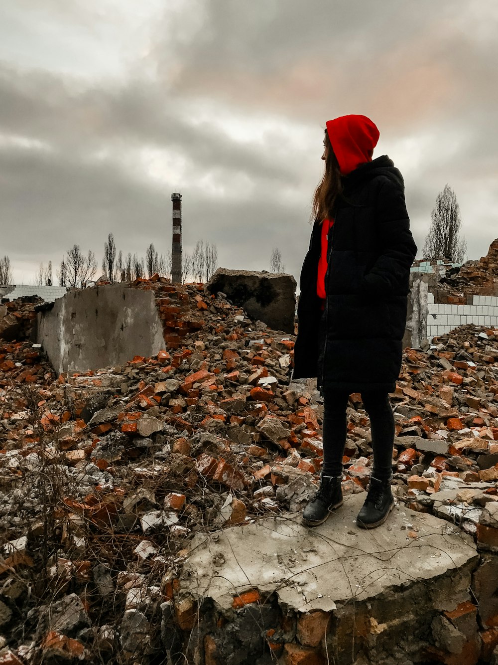 woman in black jacket standing on rocky ground under cloudy sky during daytime