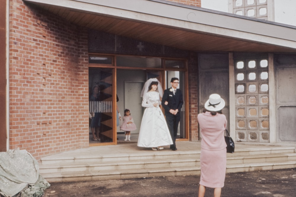 man and woman standing in front of brown wooden building during daytime