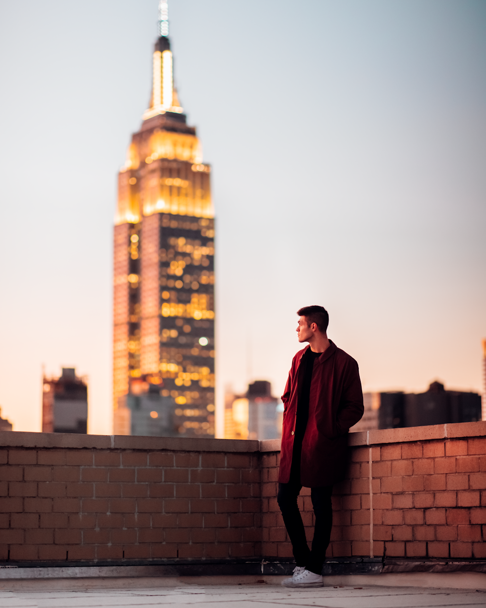 homem em casaco vermelho em pé no telhado olhando para o grande ben durante o dia