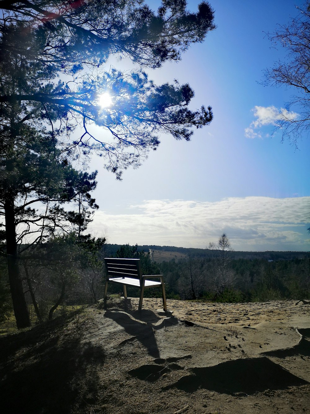 brown wooden bench on brown dirt ground near green grass field during daytime