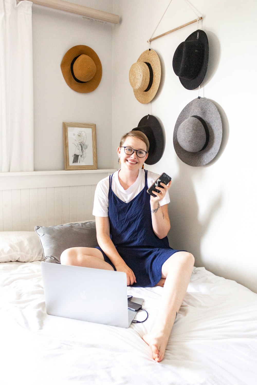 woman in blue scoop neck shirt sitting on bed while using macbook