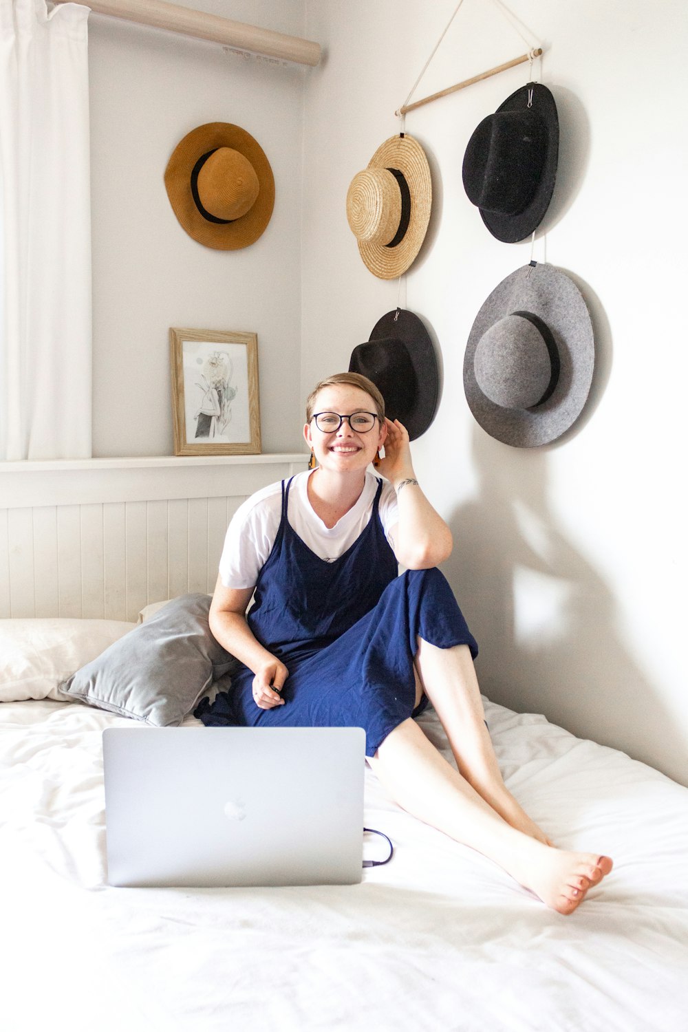 woman in blue dress sitting on bed using macbook