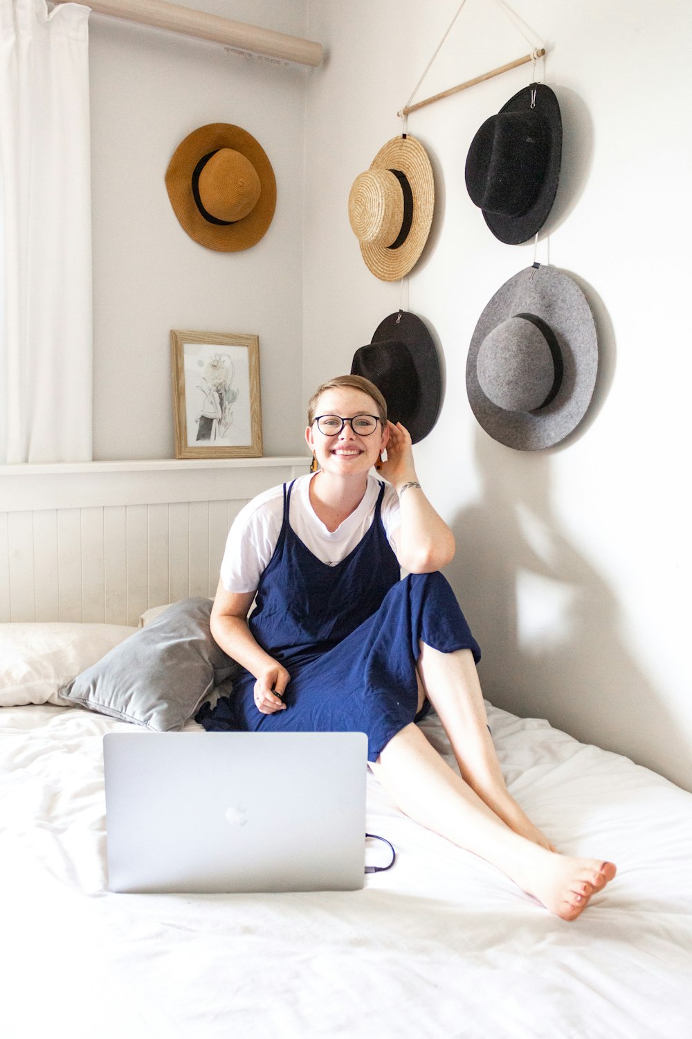 Femme en robe bleue assise sur le lit à l’aide de MacBook