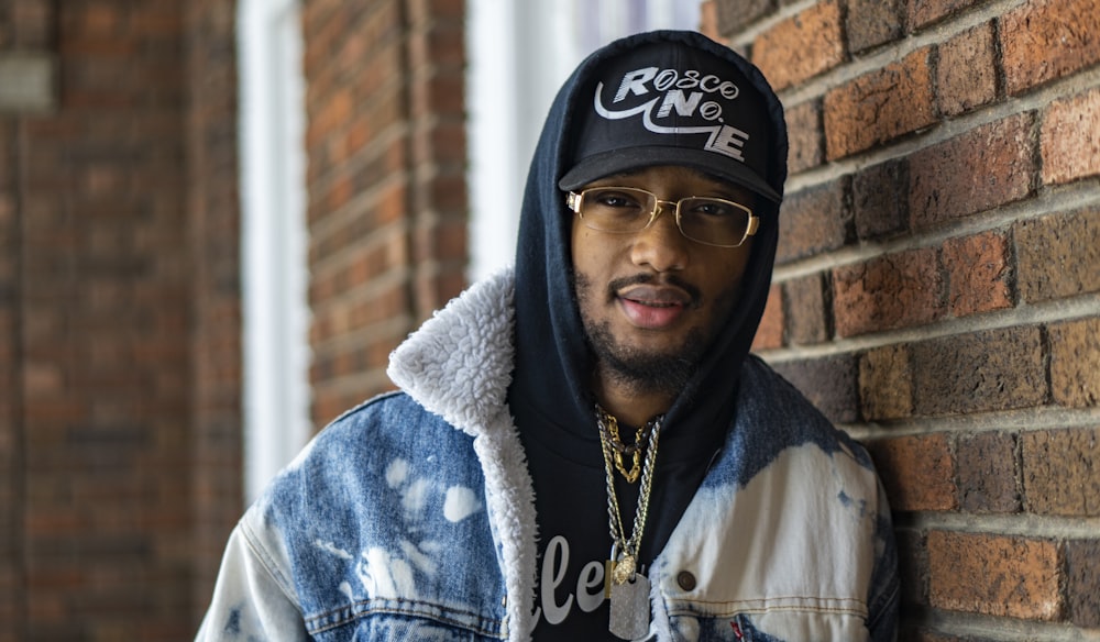 man in blue denim jacket wearing black and white cap