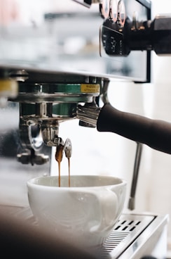 person pouring water on white ceramic cup