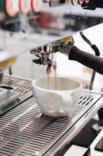 white ceramic cup on silver and black espresso machine