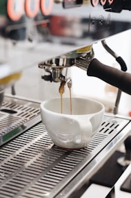 white ceramic cup on silver and black espresso machine