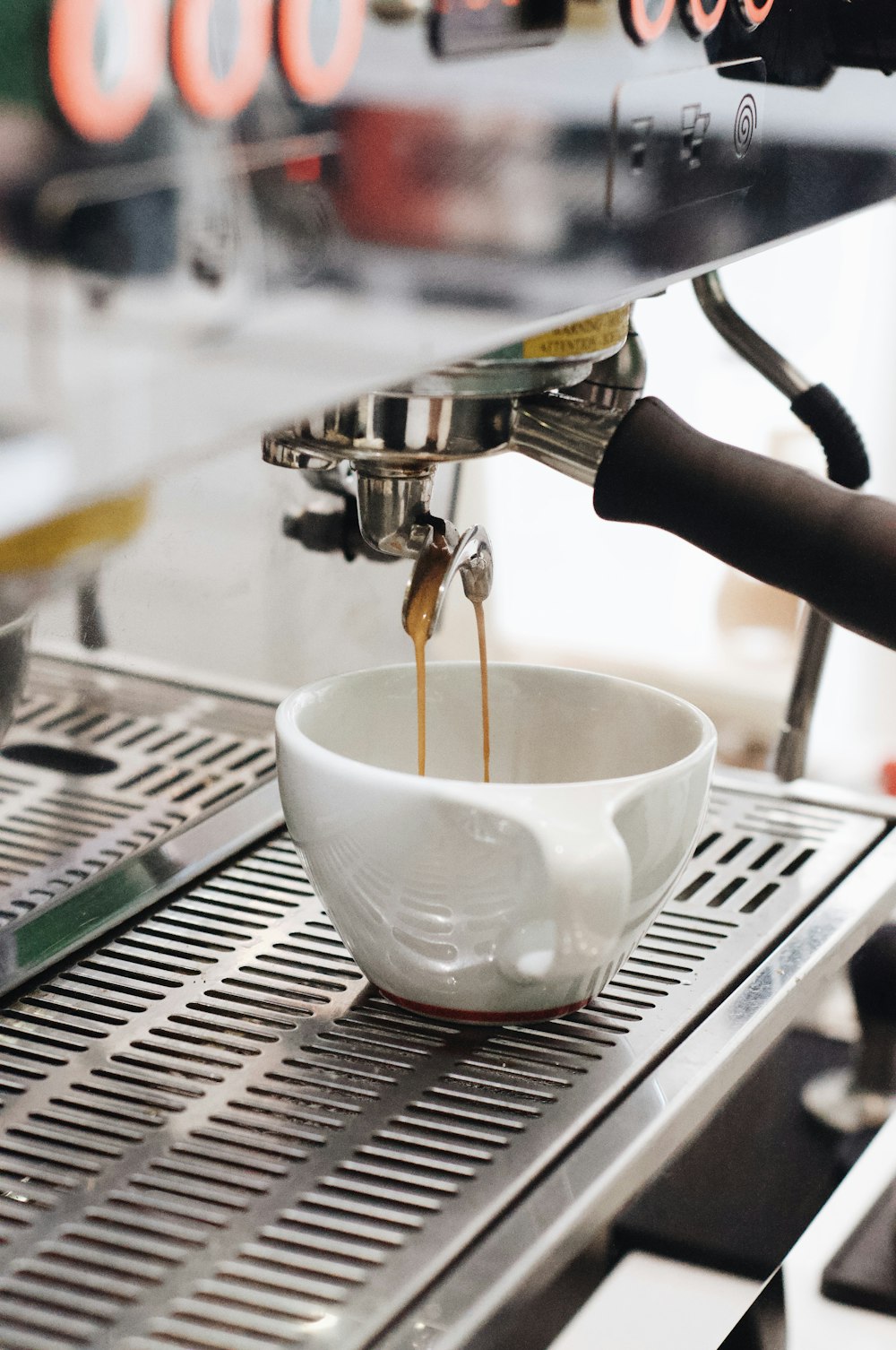 white ceramic cup on silver and black espresso machine