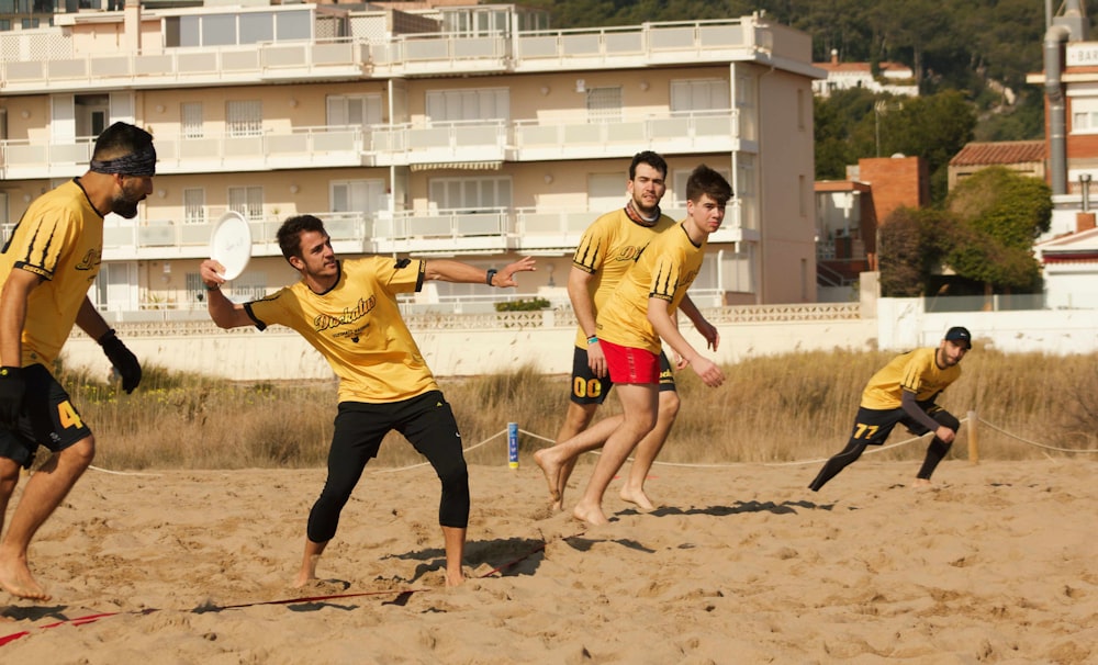 man in yellow crew neck t-shirt and black shorts running on brown sand during daytime