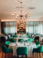 white table with green chairs and white pendant lamps