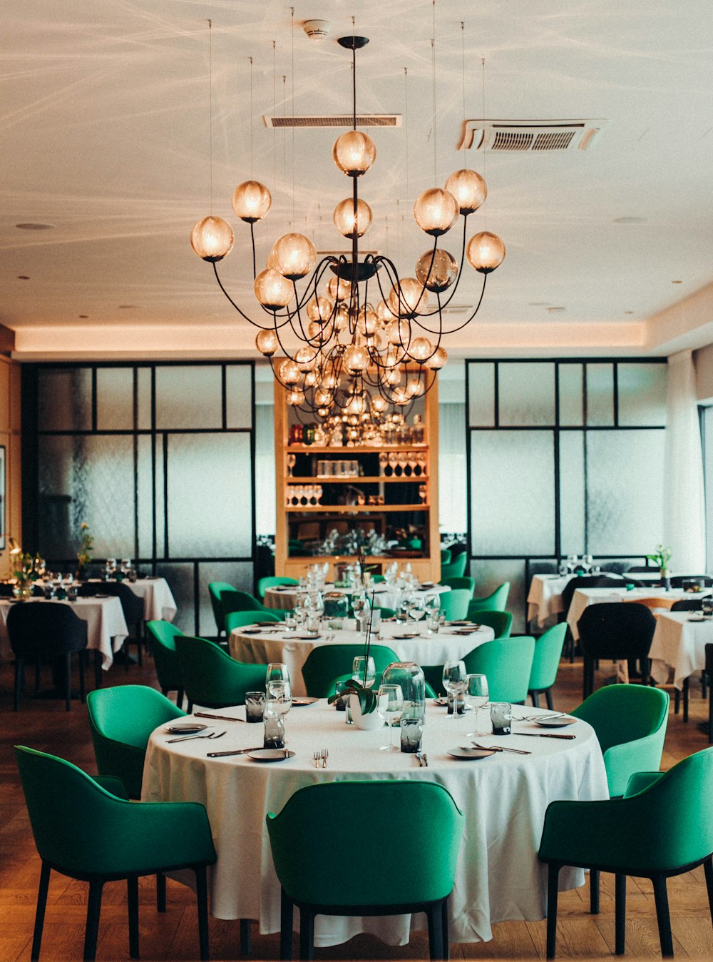 white table with green chairs and white pendant lamps