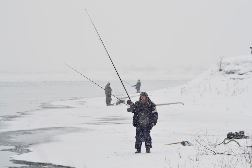 man in black jacket and blue denim jeans holding black stick on snow covered ground during