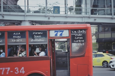 A 77transportes vehicle driving safely along a tree-lined city street.