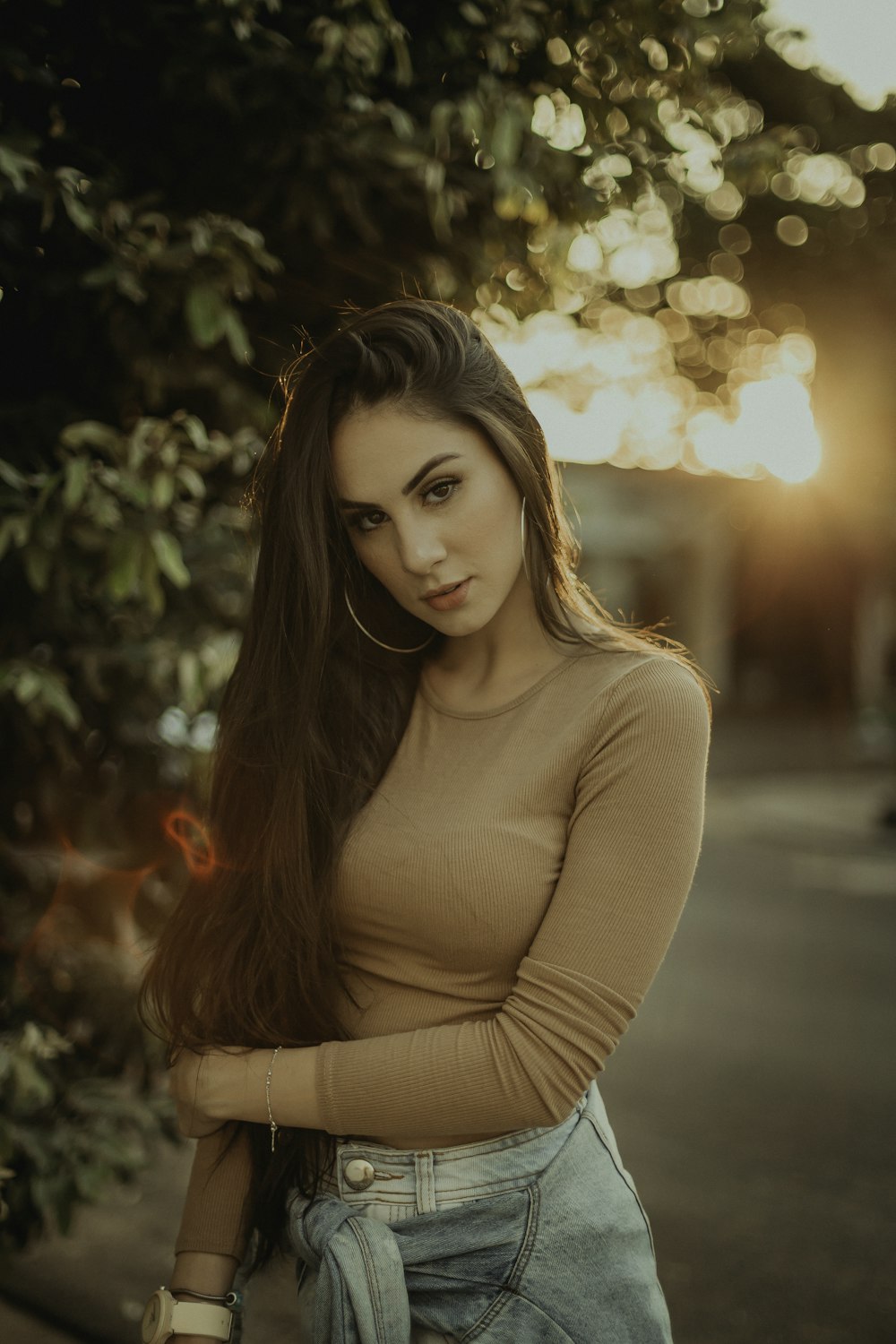 woman in brown long sleeve shirt standing near green trees during daytime