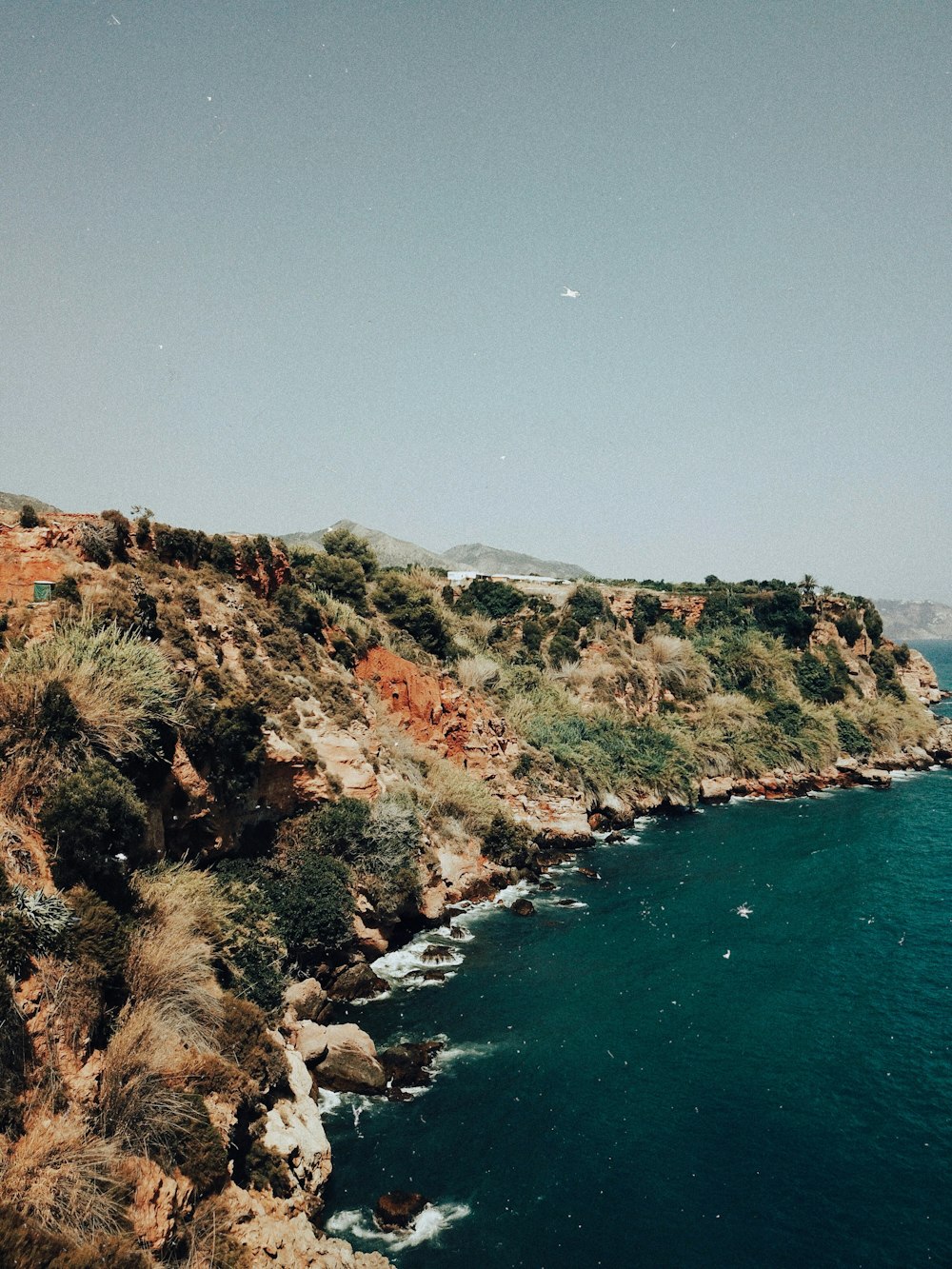 Montaña marrón y verde junto al cuerpo de agua durante el día