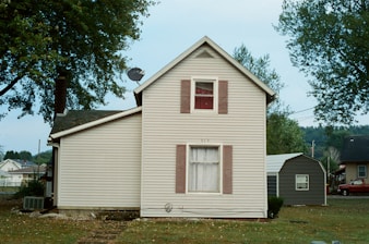 white wooden house near green trees during daytime