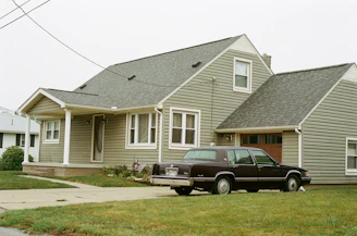 black car parked in front of white and gray house