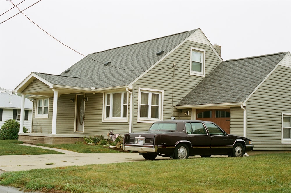 black car parked in front of white and gray house