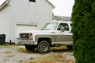 A compost pickup truck parked outside a cozy home with bins ready for collection.