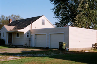 white and brown wooden house near green trees under blue sky during daytime