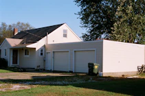 white and brown wooden house near green trees under blue sky during daytime