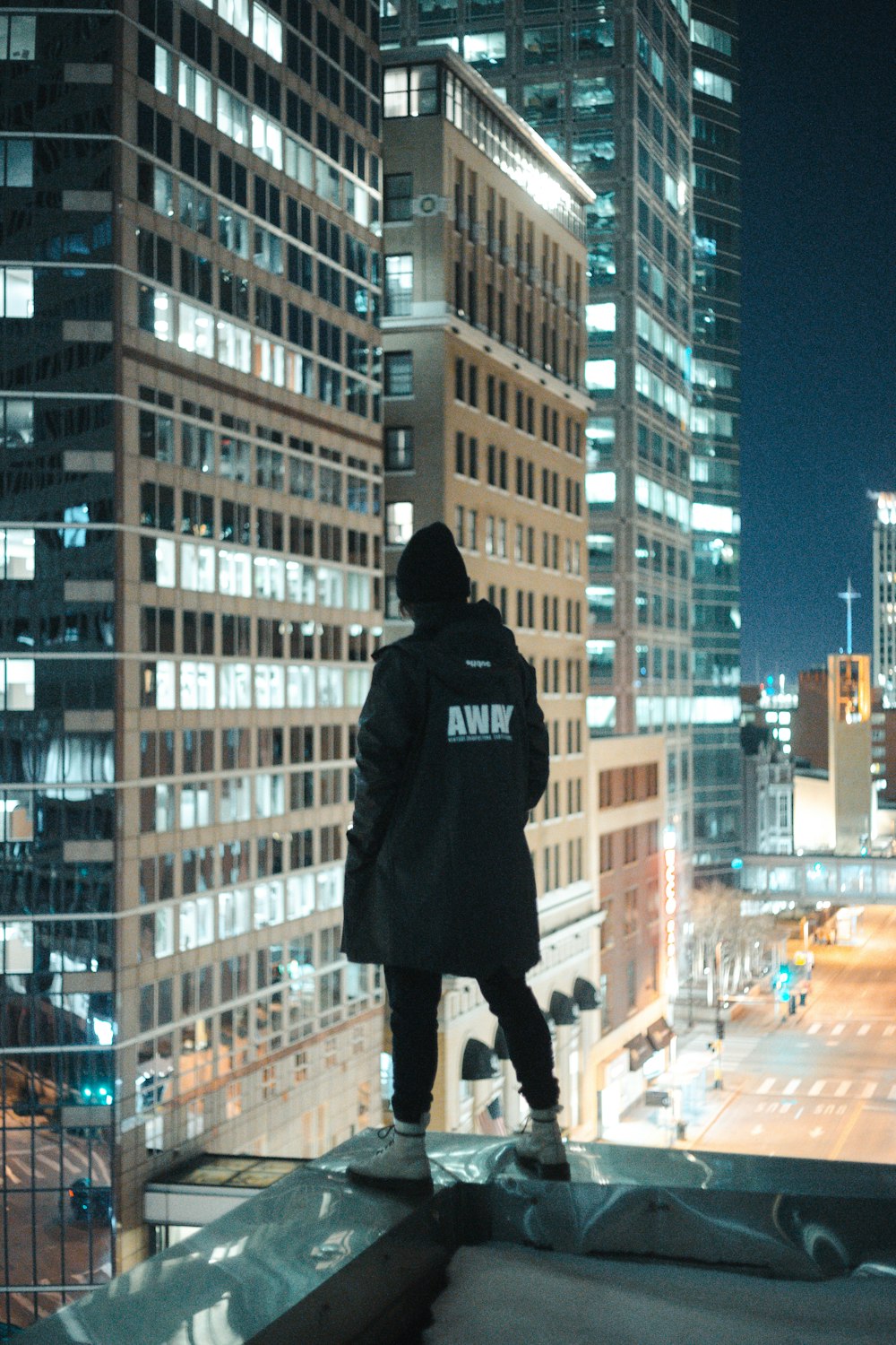 Mann in schwarzem Kapuzenpulli steht nachts auf der Straße