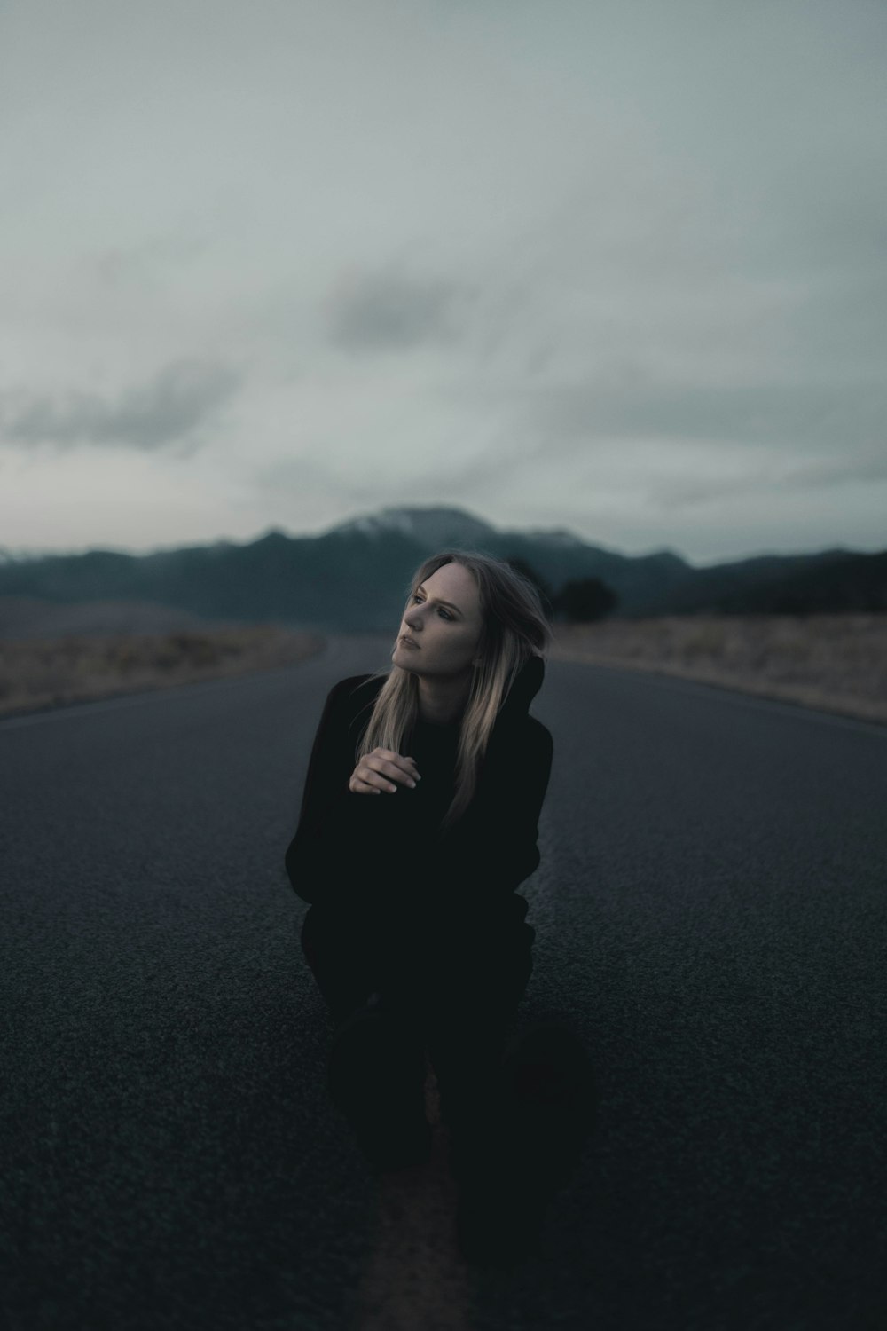 woman in black long sleeve shirt standing on black asphalt road during daytime