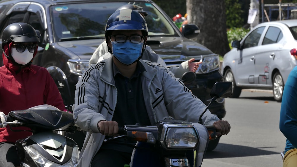 man in black jacket wearing blue helmet riding motorcycle during daytime