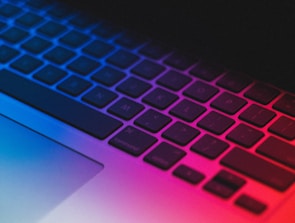 A futuristic laptop keyboard illuminated with cool blue backlighting.