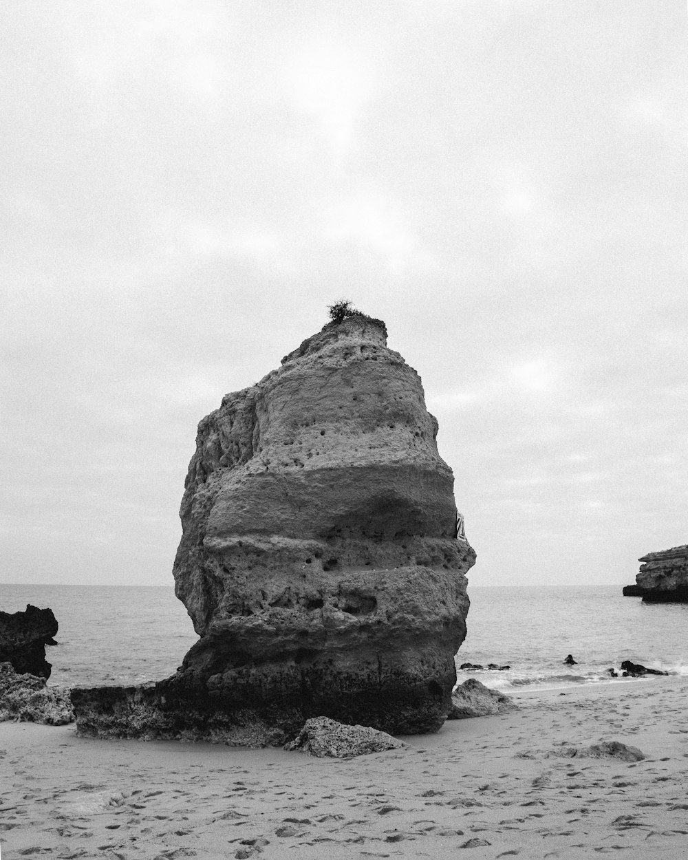 grayscale photo of rock formation on sea shore