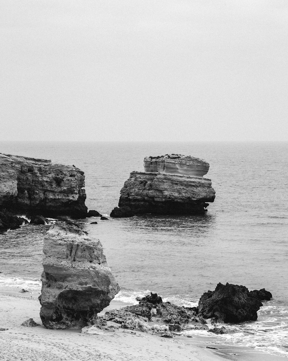 grayscale photo of rock formation on sea