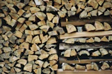 A neatly stacked pile of firewood beside a rustic cabin in the woods.