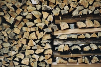 A warm, rustic stack of fuel wood logs neatly arranged outside a countryside store.