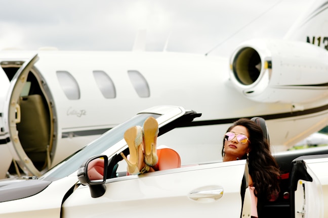 woman in black tank top holding orange and white sports car