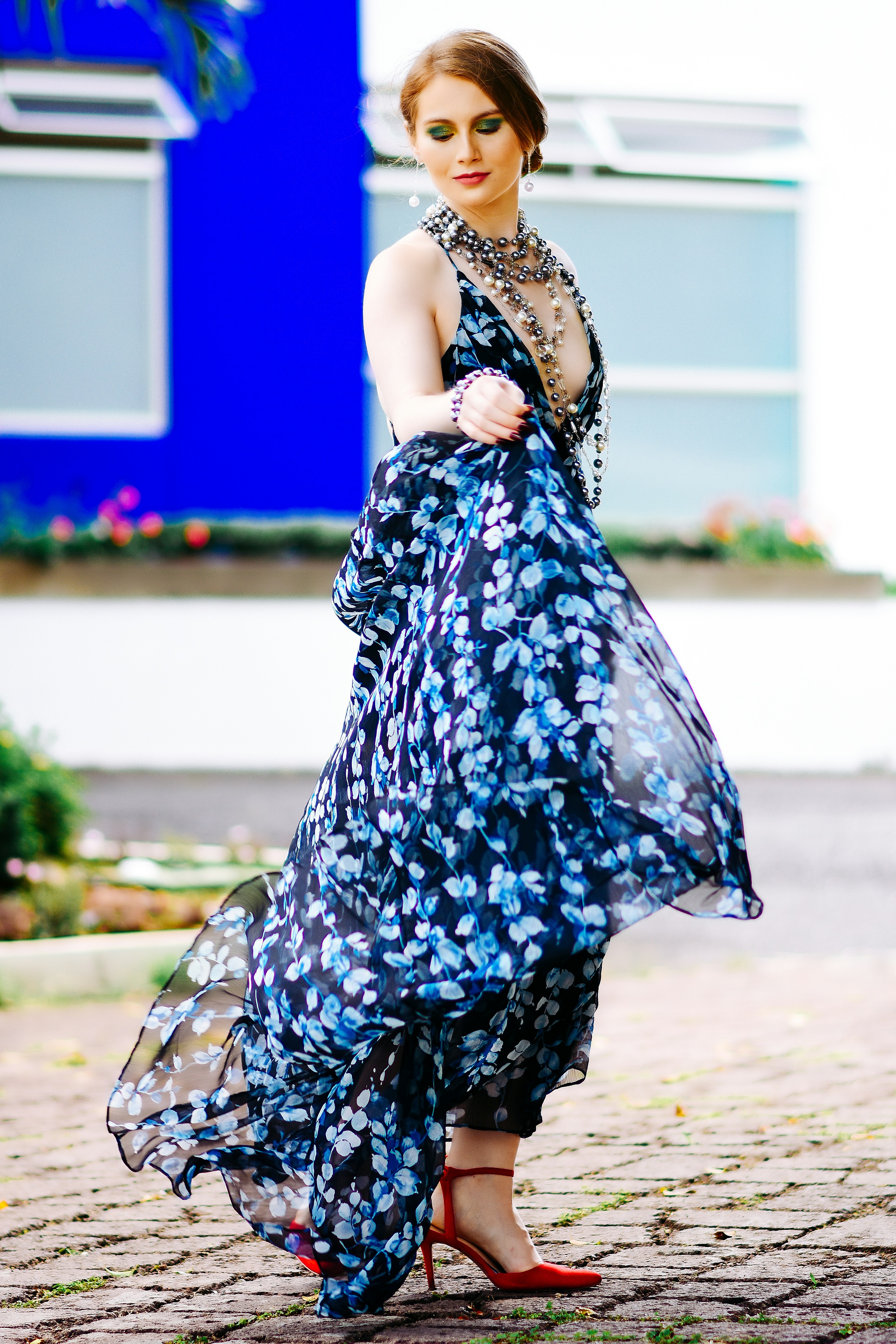 woman in blue and white floral dress standing on gray concrete floor