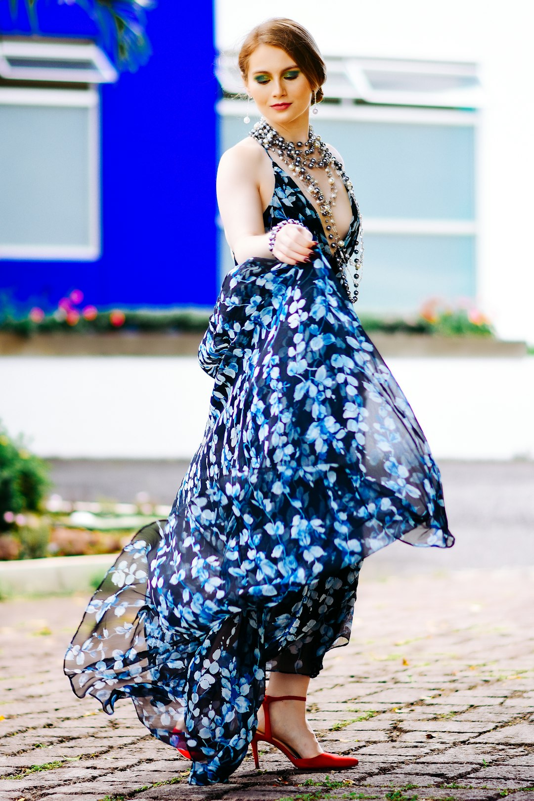 woman in blue and white floral dress standing on gray concrete floor