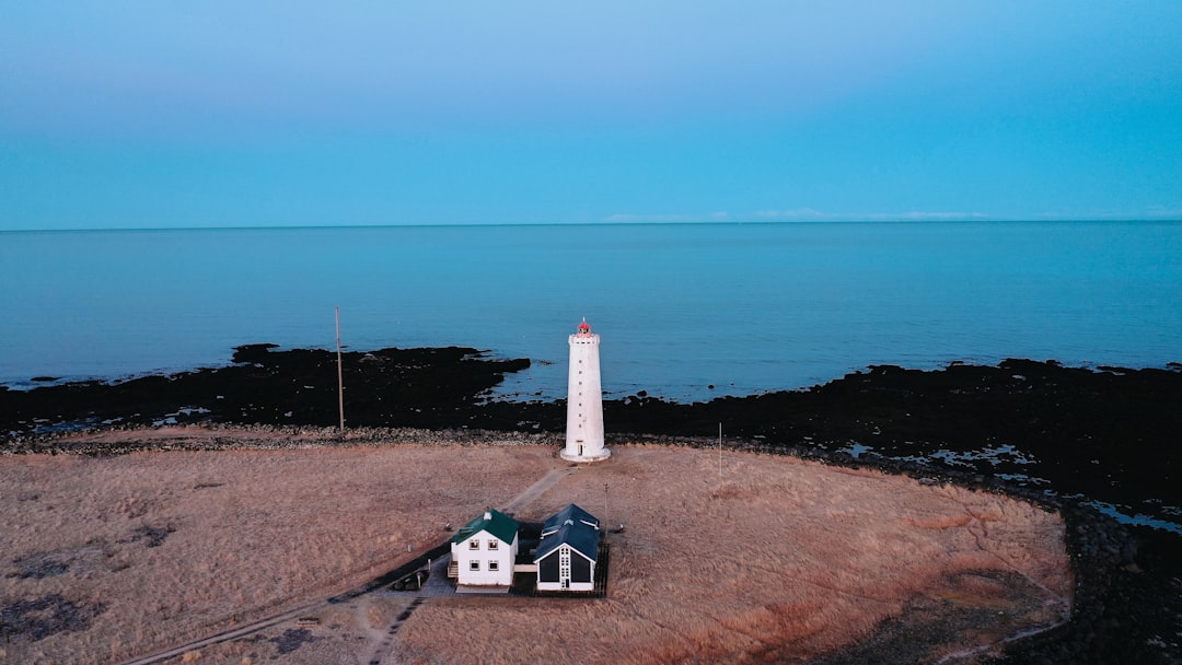 white and red lighthouse near body of water during daytime