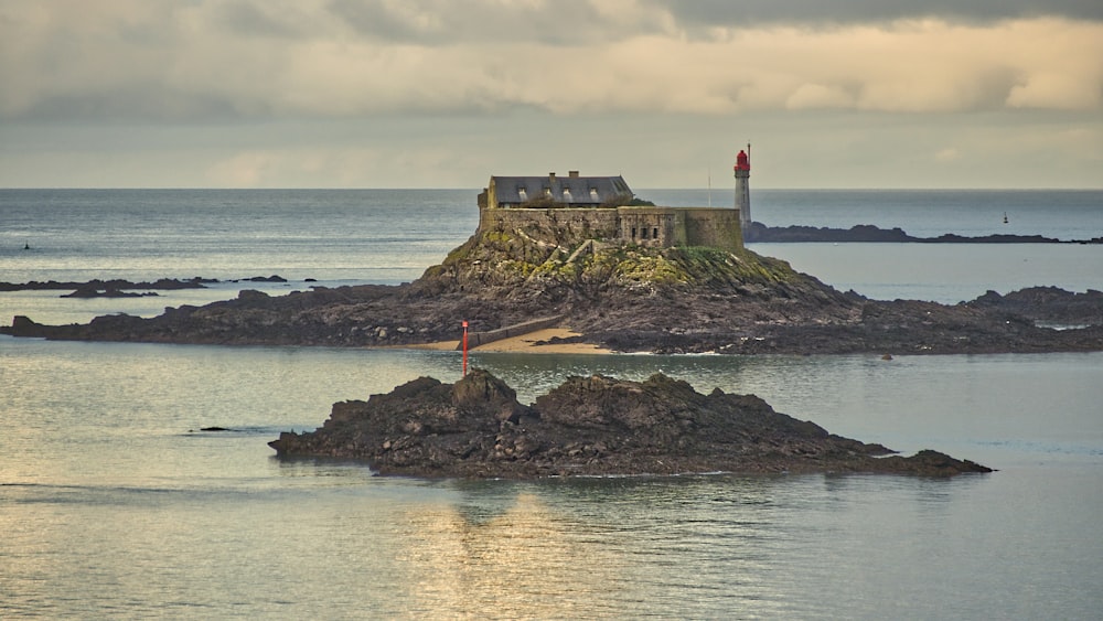 white and red lighthouse on brown rock formation near body of water during daytime