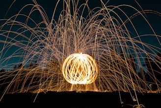 A vibrant display of light trails creating a spherical pattern, with bright, swirling lines against a dark background. The scene appears dynamic and lively, with the light arcs suggesting motion and energy.