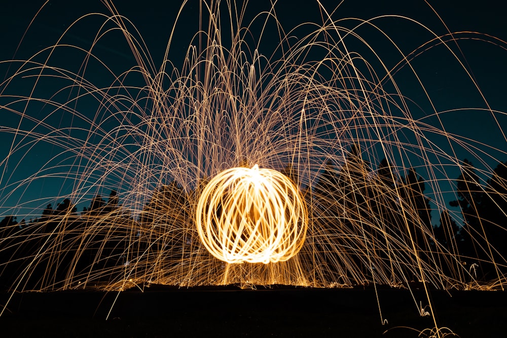 steel wool photography of man standing on field during night time