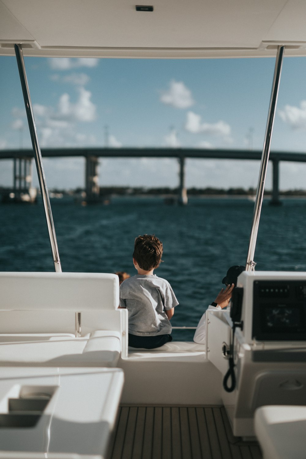 boy in white and blue shirt sitting on white boat during daytime