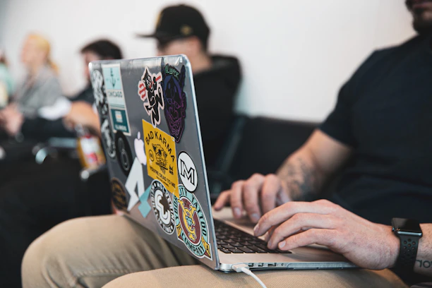 A person working on a laptop with multiple language flags floating around.