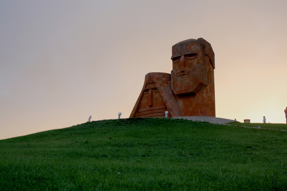 brown concrete statue on green grass field during daytime