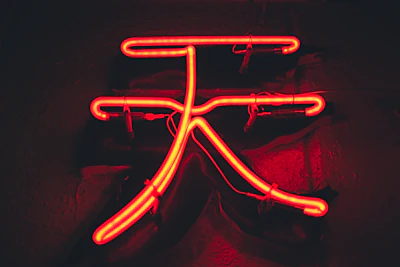 Close-up of a glowing neon sign with cryptic symbols against a black background.