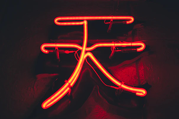 An artistic close-up of a scarab-inspired symbol illuminated in vibrant rainbow neon hues.