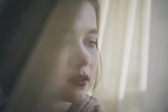 A close-up portrait of a thoughtful person looking into the distance with soft lighting.