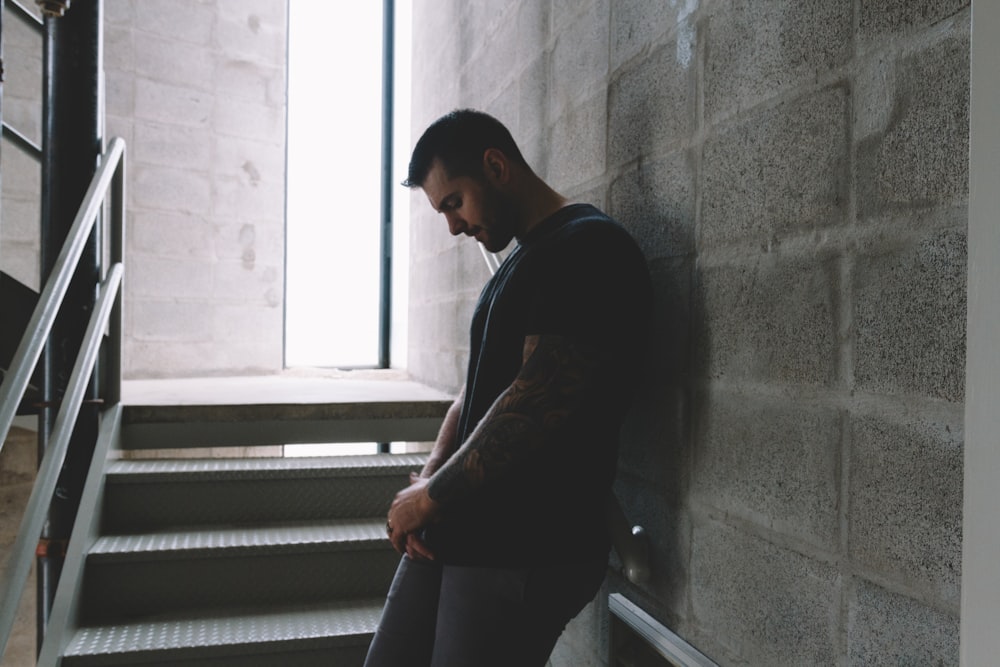 man in black t-shirt and brown pants standing on staircase