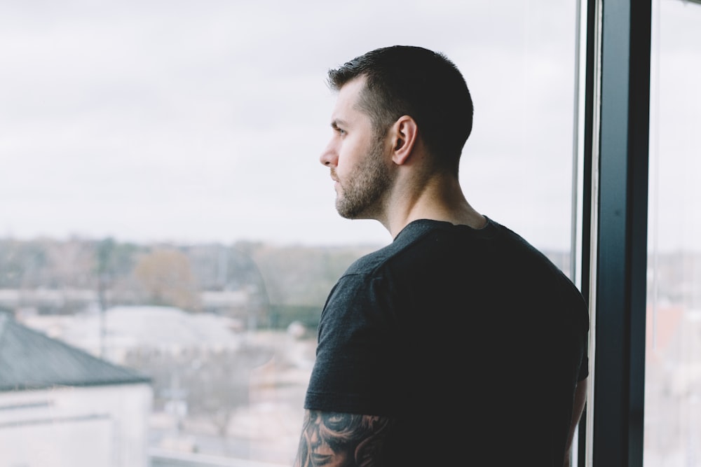 man in black crew neck shirt standing on top of building during daytime