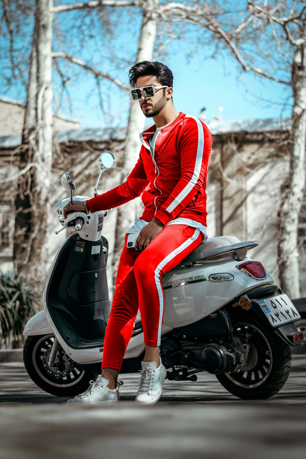 man in red and blue jacket and red pants riding on red and white motorcycle during