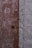Two adjoining doors with a weathered appearance, one brown and one gray. The finish is distressed with visible signs of wear and peeling paint. A round metal doorknob is present on the brown door.